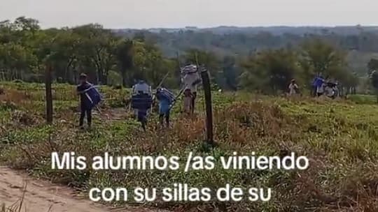 En Caaguazú, niños cargan sillas para estudiar en una precaria escuelita con techo de zinc